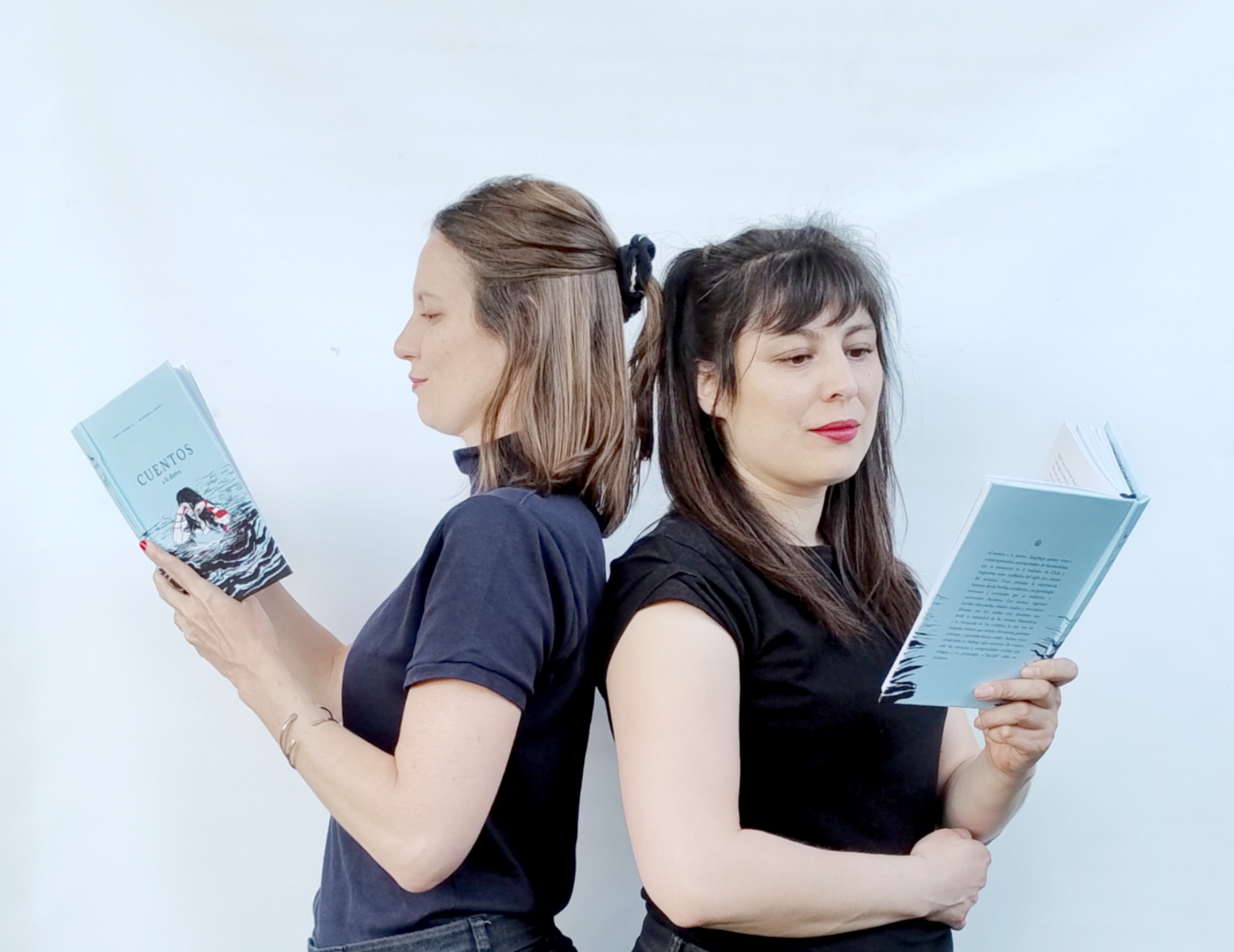 Romina Guerra y Antonella Nanni de espaldas, cada una con un ejemplar de Cuentos a la deriva